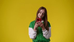 4k video of one girl who enjoys a message on her phone over yellow background.