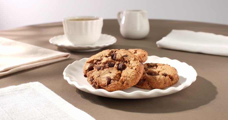cookies with coffee on a brown background. american chocolate chip cookie closeup. pastries on the table. sweets on a plate on a sunny day Royalty-Free Stock Footage #1103361951