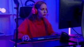 Close up portrait of asian young Gamer woman with headphones excited playing online video game. Room and PC have colorful neon LED lights. Happy girl smile happiness celebrate trump up good.