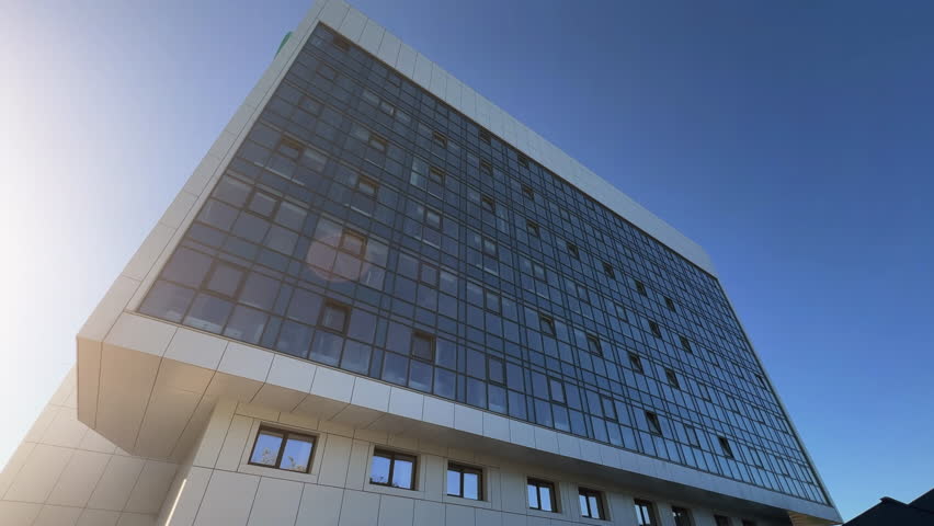 Modern hospital building with a glazed exterior. Bottom up view of the clinic windows. Extreme wide angle shot