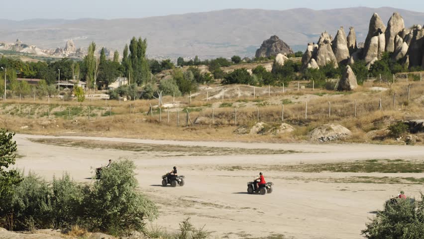 A group of tourists riding ATVs on the sand in the national park. With mountains and rocks in the background. Extreme holiday fun