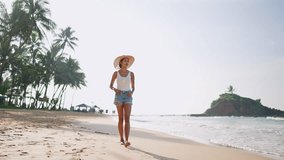 Multiethnic black woman walking on ocean beach on her tropical vacation at exotic island. African american female goes on sea shore enjoying the sun in straw hat. Bipoc girl relaxing on travel tour. - Powered by Shutterstock - Get 15% off with code: PIKWIZARD15