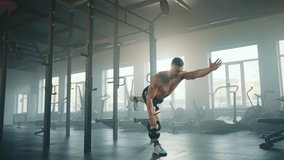 Athletic young man pulls heavy kettlebell up with one hand doing single leg stand in fully-equipped gym. Sportsman holds balance with outstretched arm. High quality 4k footage - Powered by Shutterstock - Get 15% off with code: PIKWIZARD15