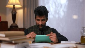 Front view excited Middle Eastern man rejoicing passing exam checking result online on digital tablet. Portrait of happy handsome young male student with books at home indoors gesturing success - Powered by Shutterstock - Get 15% off with code: PIKWIZARD15