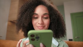 Woman Scrolling Smartphone at Camera. 20s mixed race female using telephone sitting on sofa at home. Young adult person mobile phone addicted. - Powered by Shutterstock - Get 15% off with code: PIKWIZARD15