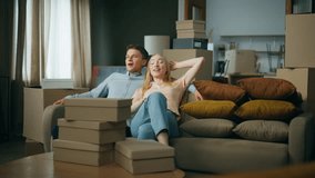 Satisfied young couple sitting on sofa excited about moving new house. Attractive man hugging blond woman relaxing in comfortable room surrounded by cardboard boxes. Married pair enjoying relocation. - Powered by Shutterstock - Get 15% off with code: PIKWIZARD15