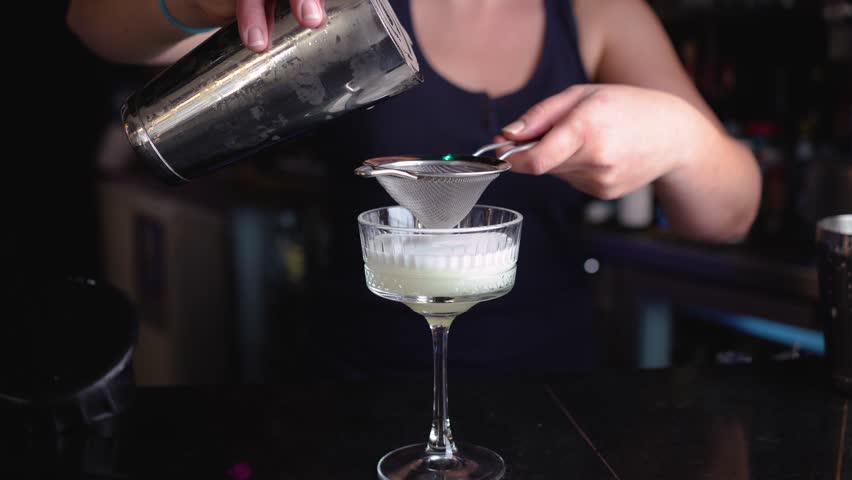 Woman straining a cocktail from the shaker