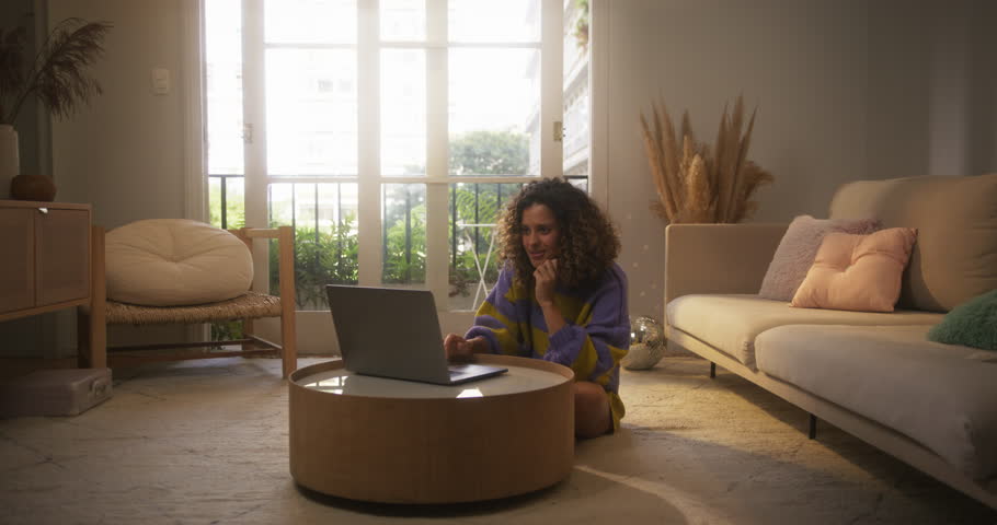 Portrait of Smiling Young Woman Working from Home on Laptop Computer in Sunny Apartment. Successful Creative Female Entrepreneur Does Remote Job for Marketing Project, Sending Emails to Colleagues