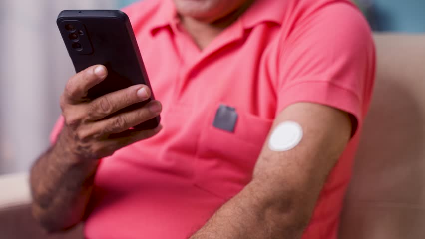 Close up shot of senior man checking sugar or glucose level by tapping mobile phone to sensor at home - concept of technology, diabetes and health care Royalty-Free Stock Footage #1103386495