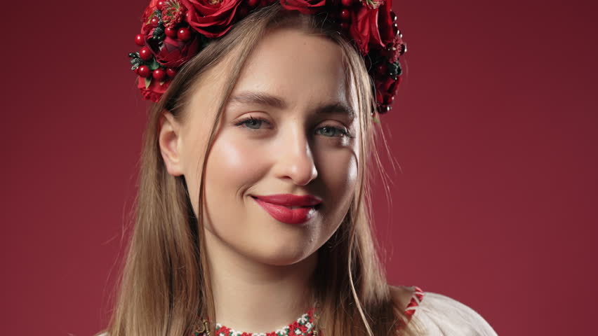 Beautiful ukrainian woman in ethnic costume on red studio background.