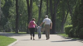 Elderly grandparents holding hands of kid and rising him on park alley - Powered by Shutterstock - Get 15% off with code: PIKWIZARD15