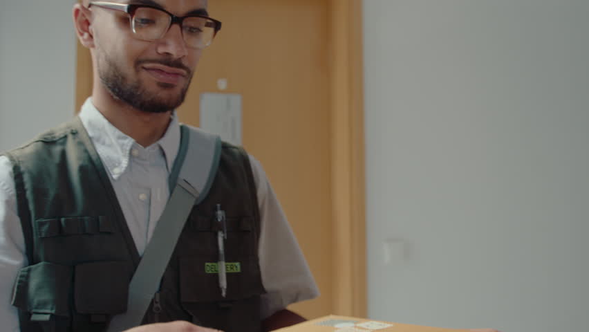 Young male postal service worker delivering express mail to female recipient at home, asking to sign a document, then saying bye and leaving Royalty-Free Stock Footage #1103398083