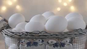 mesh vintage metal basket with fresh white chicken eggs on wooden table, valuable food product, Easter culinary traditions, close-up of egg white and yolk in lime transparent shell, video