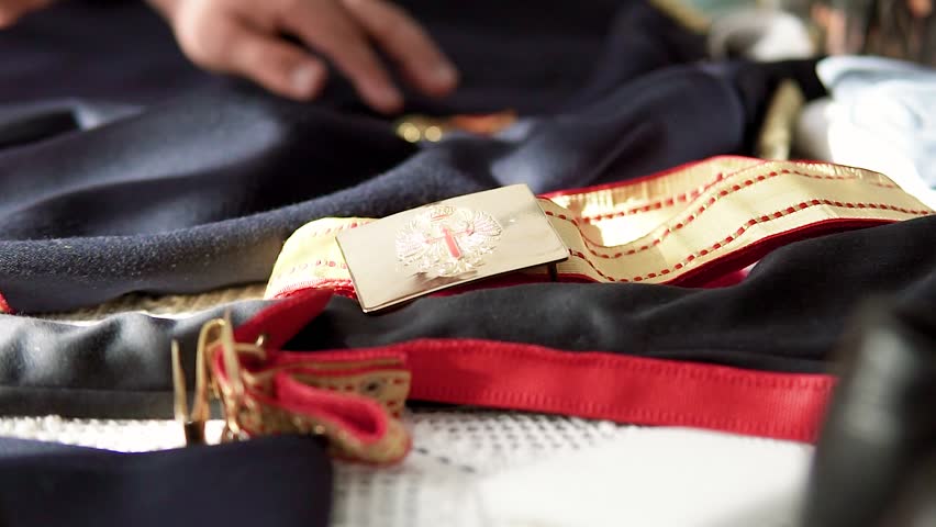 Close-up details of the military uniform on a bed prepared for a wedding.