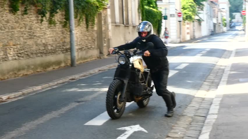 Man in helmet moving Motor bike in streets of French European town in France.