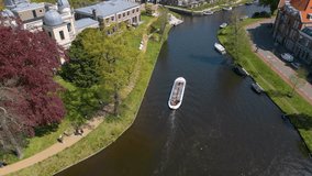 This aerial drone video shows the canals of Leiden, a city in Zuid-Holland. A tourist boat is sailing on the canal which is surrounded by beautiful dutch houses.