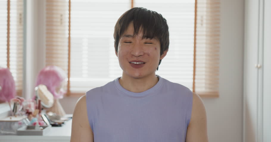 Gen Z Gay queer man non-binary beauty blogger makeup artist at home. Real asia LGBT young guy adult people happy relax smile sitting at mirror dressing room looking at camera proud and LGBTQ pride.