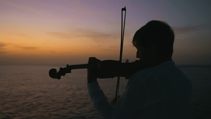 attractive young male violin player playing beautiful romantic melody in nature silhouette of young man figure in the sunrays playing the violin, boy relaxing and moving bow along the strings of a Royalty-Free Stock Footage #1103412293