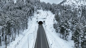 The car passes through a mountain tunnel. the driver drives the car through the winter mountains,the car enters the tunnel through the mountain and leaves it. Aerial view high quality video