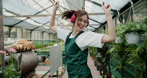 Nature's Dance: A Joyful Journey Through a Flower Shop. A girl in a green apron is a happy employee of flower shops dancing in the store