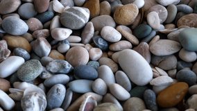4K video of colored smooth pebbles and seashells texture in rotation closeup view
