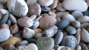 Rotation pattern of round sea stones mixed with small shells 4K video 
