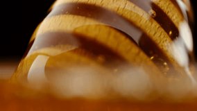 Honey dripping from honey dipper, isolated on black background. Thick organic honey dripping from a wooden honey spoon - Powered by Shutterstock - Get 15% off with code: PIKWIZARD15
