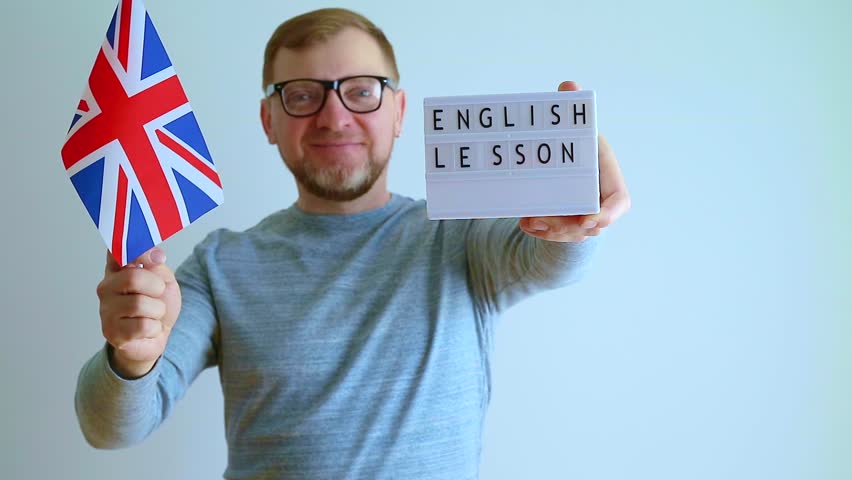 Teacher shows the flag of Great Britain and a sign with the inscription English lesson. Learning concept.