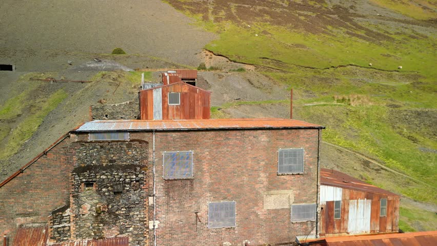 Reveal of abandoned mine buiding with rusty roof at Force Crag Mine Coledale Beck in the English Lake District