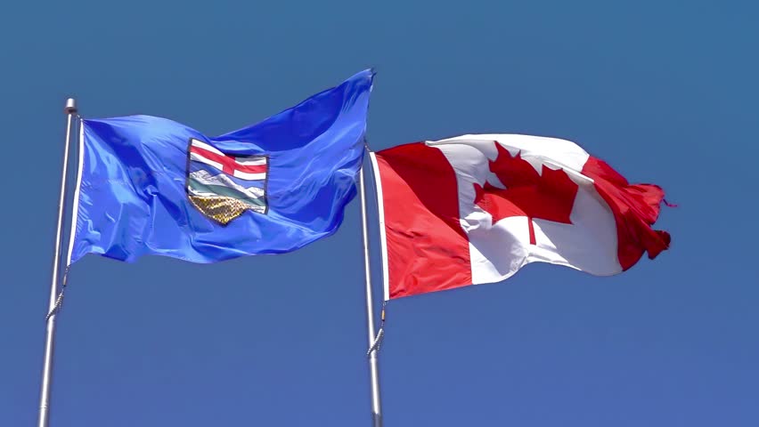 Slow motion of a waving Alberta and Canada flag on a blue sky. Royalty-Free Stock Footage #1103441663