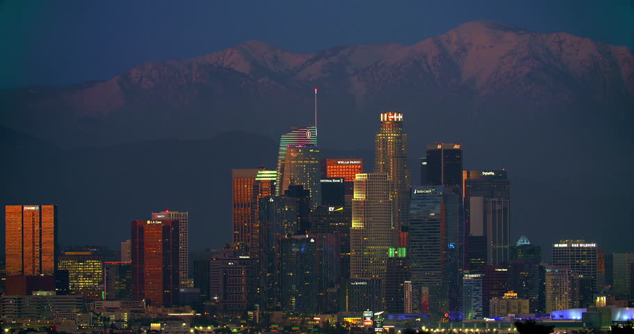Los Angeles Downtown financial and business towers skyscrapers skyline and mountains with snow in the background at night, California, 4K