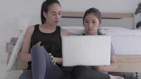 Two young asian woman practicing online yoga exercise with laptop