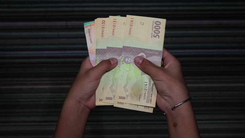 A child is counting rupiah notes in five thousand denominations | Shutterstock HD Video #1103447787