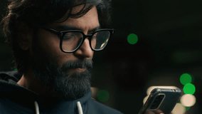 Close up Indian bearded man in glasses at dark parking lot underground night evening using mobile phone app chatting social media online Arabian guy Muslim male typing browsing smartphone booking taxi - Powered by Shutterstock - Get 15% off with code: PIKWIZARD15