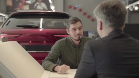 man with beard in car dealership speaks with manager with car on background - Powered by Shutterstock - Get 15% off with code: PIKWIZARD15