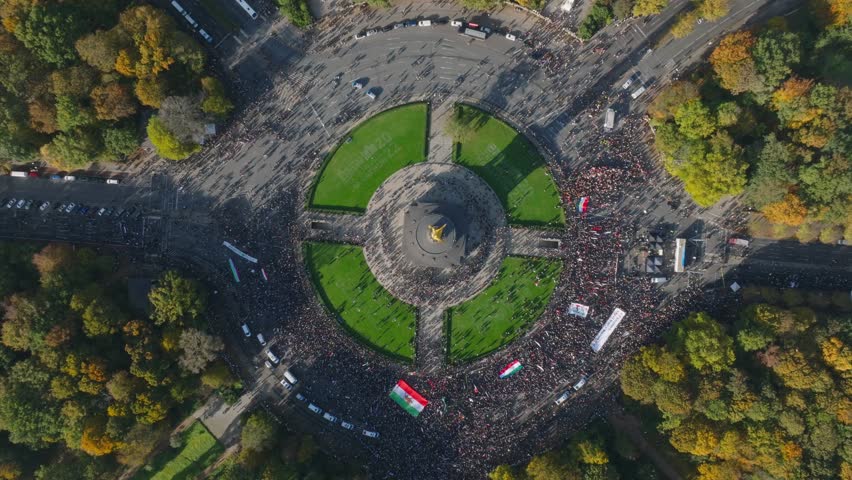 Iranians protesting on square. Overhead ascending footage of symmetrical square with large roundabout and victory column in centre. Berlin, Germany