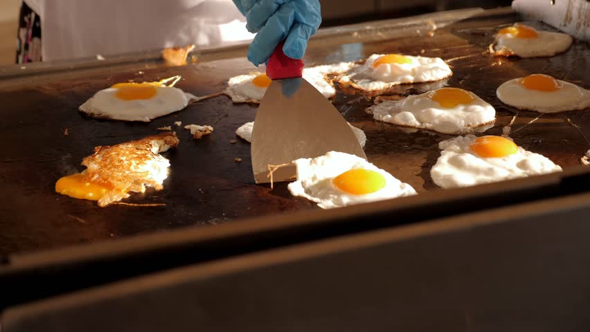 A lot of eggs are fried on a large professional oven in the hotel restaurant. The power system is all inclusive.  Royalty-Free Stock Footage #1103451611