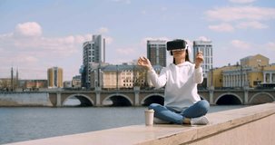 4k video - meditation and escape from reality in the midst of a bustling city. Modern VR meditation - woman practices yoga and meditation with virtual reality technology.