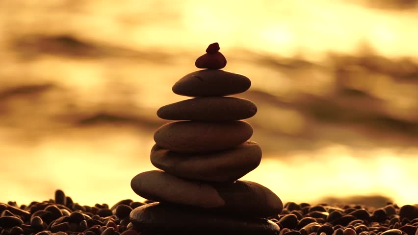 Balanced rock pyramid on pebbles beach, sunny day and clear sky at sunset. Golden sea bokeh on background. Selective focus, zen stones on sea beach, meditation, spa, harmony, calm, balance concept. Royalty-Free Stock Footage #1103457255