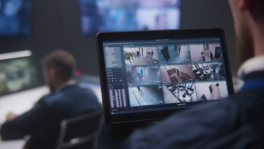 Close up shot of security operator zooming CCTV cameras with AI facial recognition using tablet in police surveillance center. Colleagues work at background. Monitoring system. Social safety concept. Royalty-Free Stock Footage #1103458769