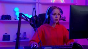 Close up portrait of asian young Gamer woman with headphones excited playing online video game. room and PC have colorful neon LED lights. Speak and command in team. happy celebrate to victory.
