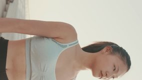 VERTICAL VIDEO, girl in sports top walking outside at morning time