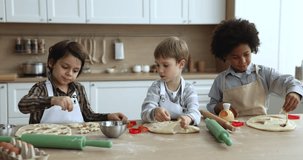 Diverse team of boys cutting dough for cookies, biscuits, training culinary, baking skills, preparing sweet bakery snacks, pastry dessert for family holiday, talking at floury kitchen table - Powered by Shutterstock - Get 15% off with code: PIKWIZARD15
