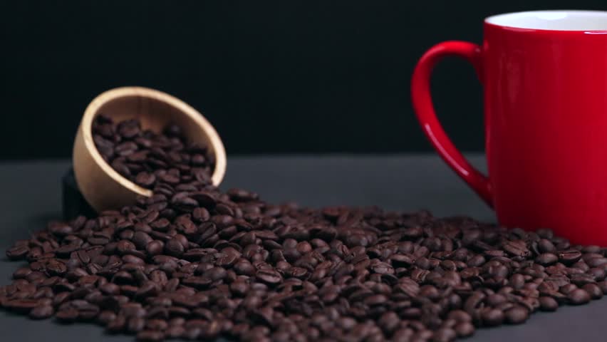 Coffee beans drop on table with wooden cup and red coffee cup texture background. bland nature excellent taste. Drink coffee in morning afternoon and evening. Quality seeds are suitable for drinkin.