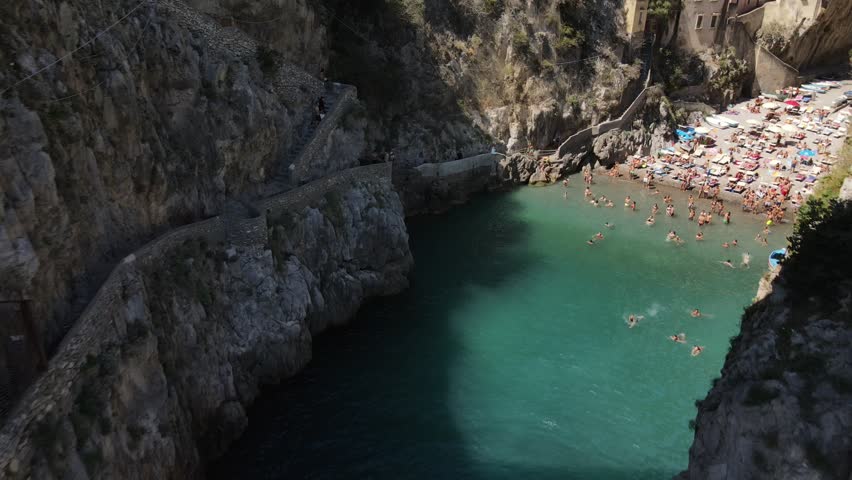 Aerial view inside bay of Fiordo di furore beach. Incredible beauty panorama of a mountains paradise. The rocky seashore of southern Italy. Sunny day. Stone bridge and sea. Amalfi Royalty-Free Stock Footage #1103474499