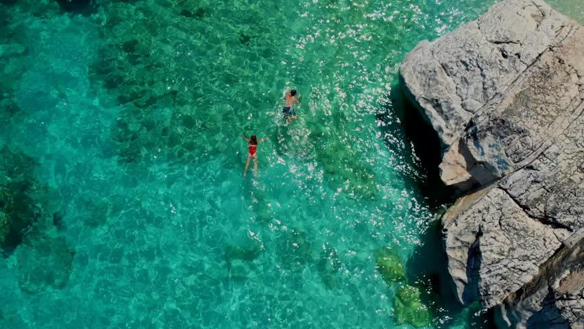 Men and women on the beach in Sardinia Italy, couple men and women playing in the ocean with crystal clear blue water snorkeling at Cala Luna Sardinia Italy Golfo Di Orosei