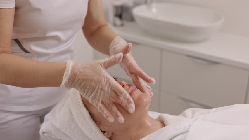 beauty spa, massage treatment, spa resort. Beauty clinic, beautiful woman has facial massage in beauty chair, laying on back, getting facelift massage, with towels on head, skin care and spa concepts