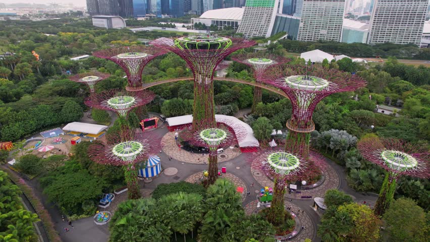 Aerial view to Cloud Forest and Flower Dome illuminated at the twilight. Famous hotel at the background. Gardens by the Bay, Singapore city in 4K.
