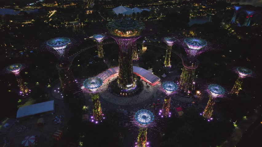 Aerial view to Cloud Forest and Flower Dome illuminated at the twilight. Famous hotel at the background. Gardens by the Bay, Singapore city in 4K. Royalty-Free Stock Footage #1103478977