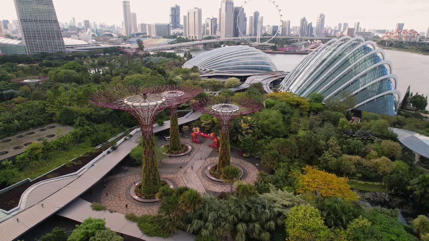 Aerial view to Cloud Forest and Flower Dome illuminated at the twilight. Famous hotel at the background. Gardens by the Bay, Singapore city in 4K.